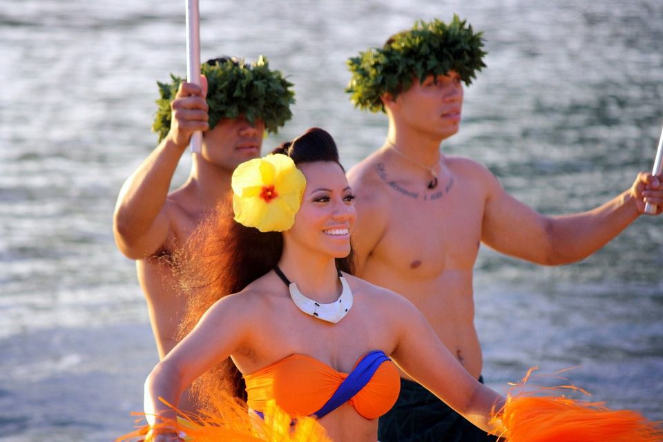 Two Hawaiian men and a Hula girl smiling.
