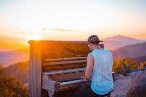 Man playing a piano into the sunset