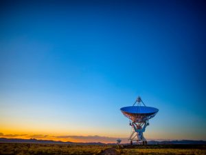 A satellite array in a field in New Mexico, during sundown.