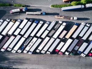Two rows of moving trucks on a parking lot, seen from above.