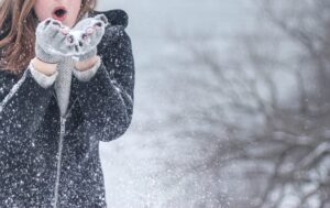 Girl blowing snowflakes from her gloves in a blizzard