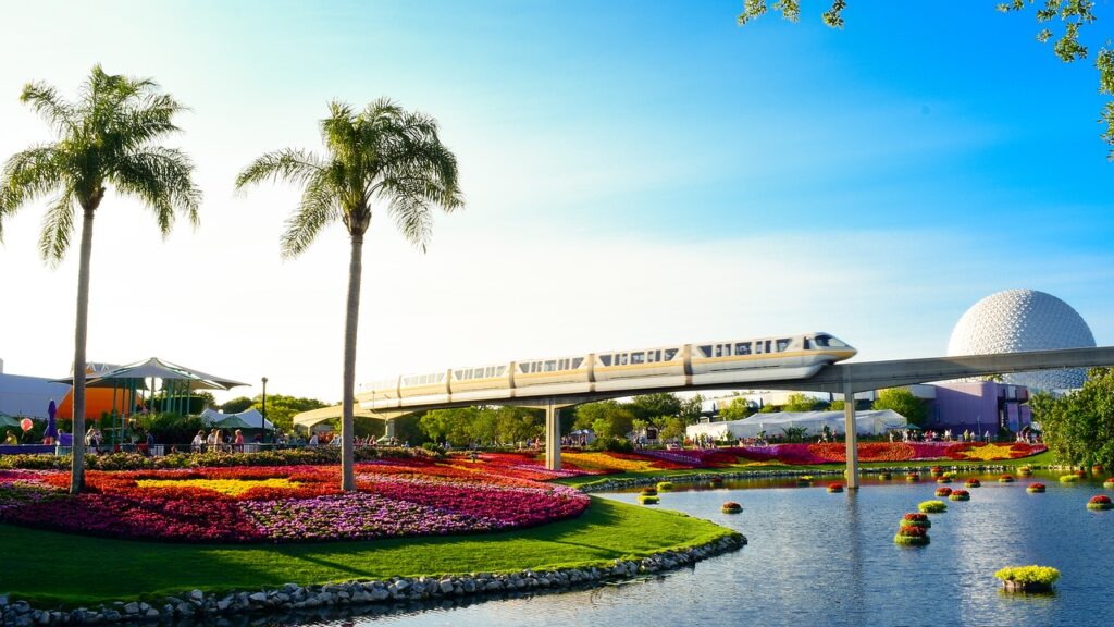 a park with colorful flowers with a train in the background