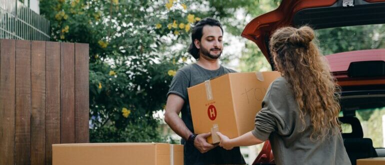 A man helping a woman carry moving boxes
