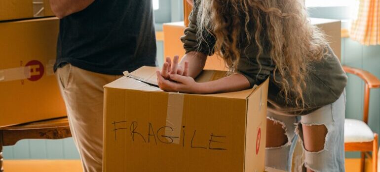 couple standing above a box marked "fragile"