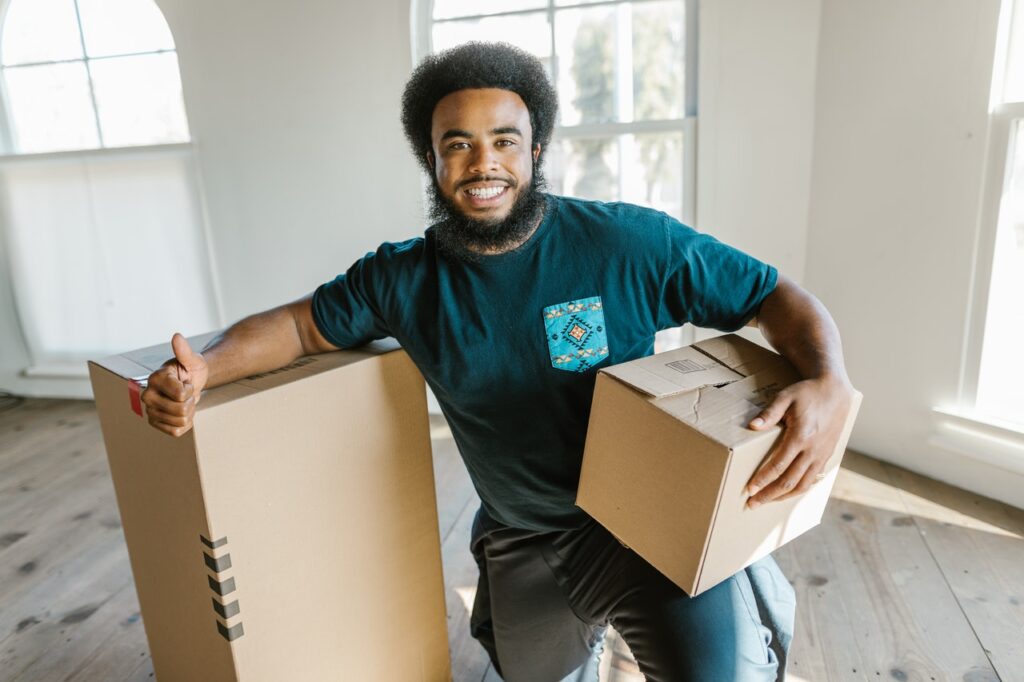 A professional mover holding a box, showing a thumbs up, representing top movers in Miami