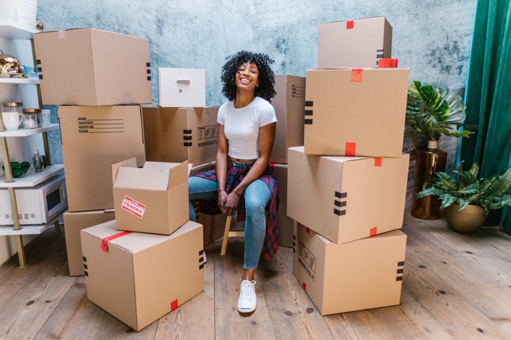 A woman sitting among boxes, smiling. 