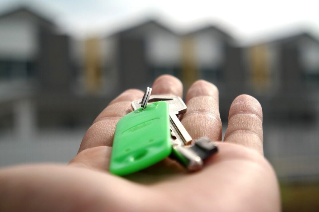A person holding a key, pointing to homes