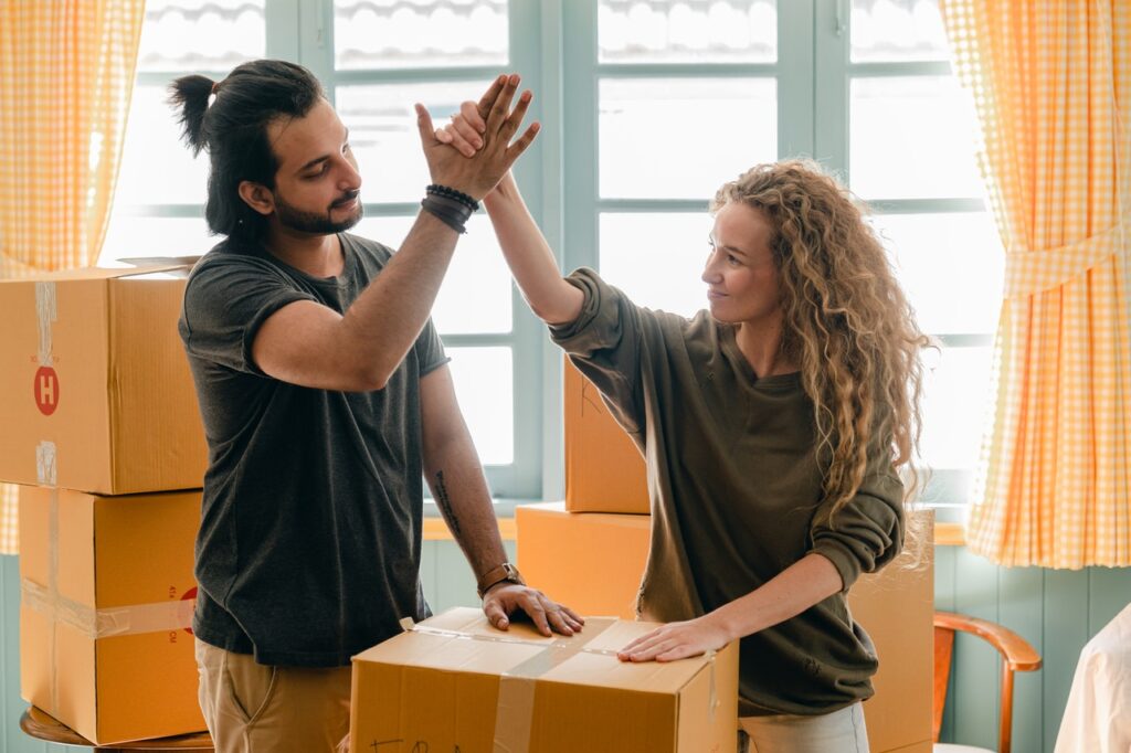 A man and a woman throwing a high-five over packed boxes