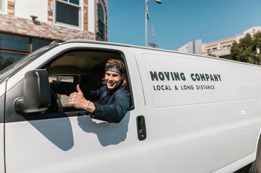 A mover showing a thumbs up from his van