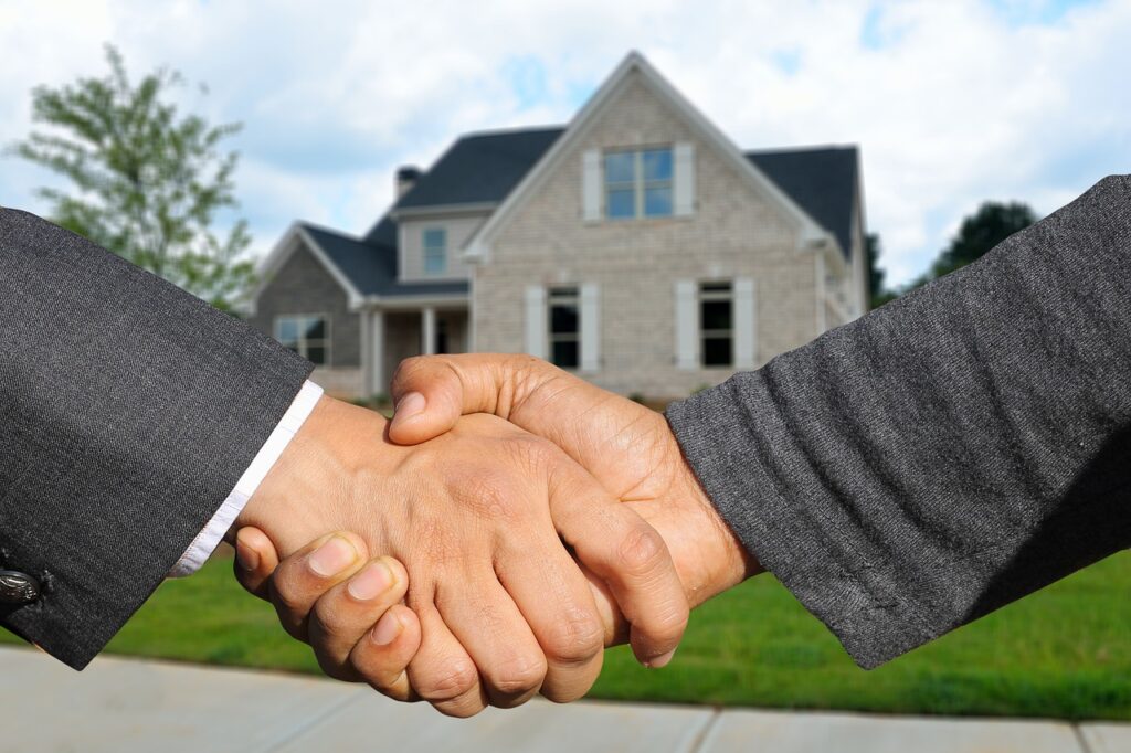Two men shaking hands in front of a house