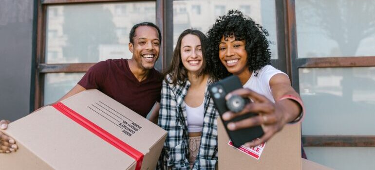 A woman taking a selfie with friends who helped her organize a DIY move.
