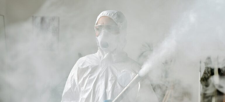 A person wearing a protection suit spraying a hazardous matter.
