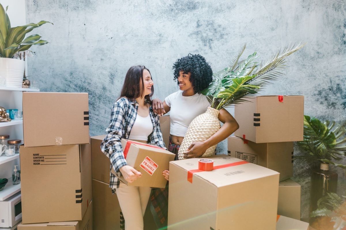 Two women surrounded by moving boxes.