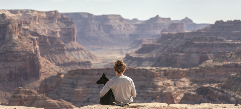 A woman hugging a dog while looking at the Grand Canyon.