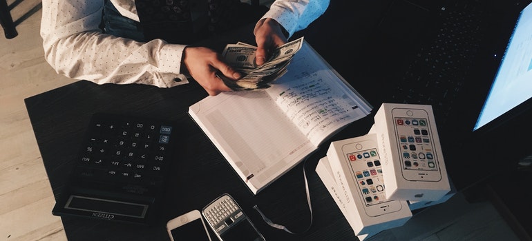 A man counting money on the desk above the notebook.