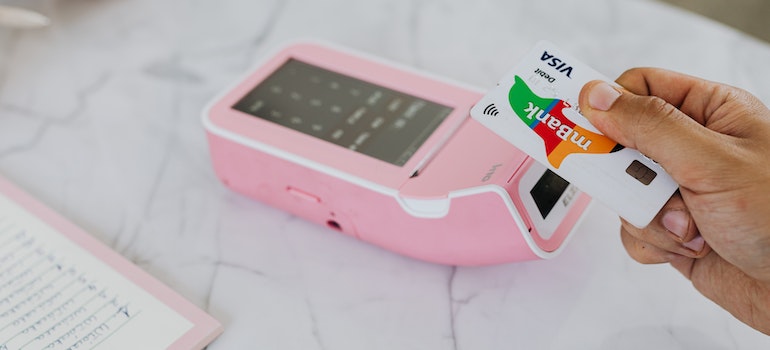 A person giving a credit card over the pink card validator.