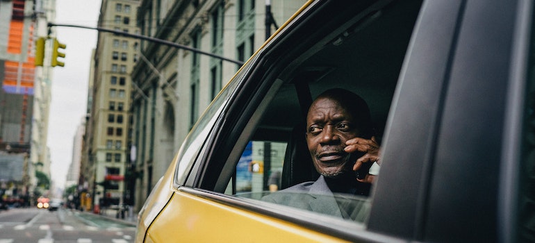 A man in NYC sitting in a cab and talking on the phone.