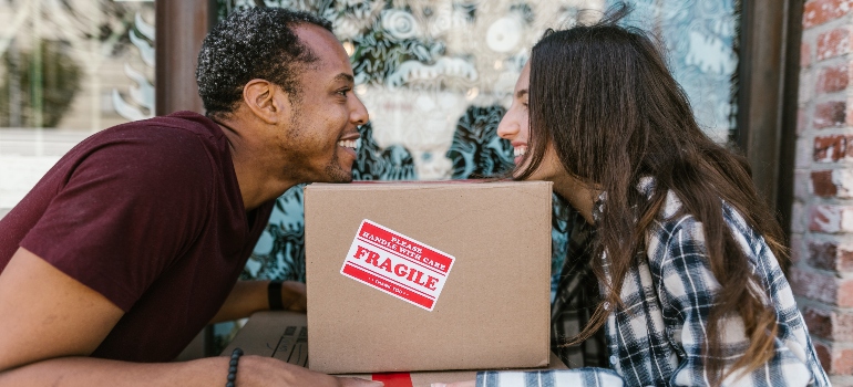 a man and a woman looking at each other while holding a box
